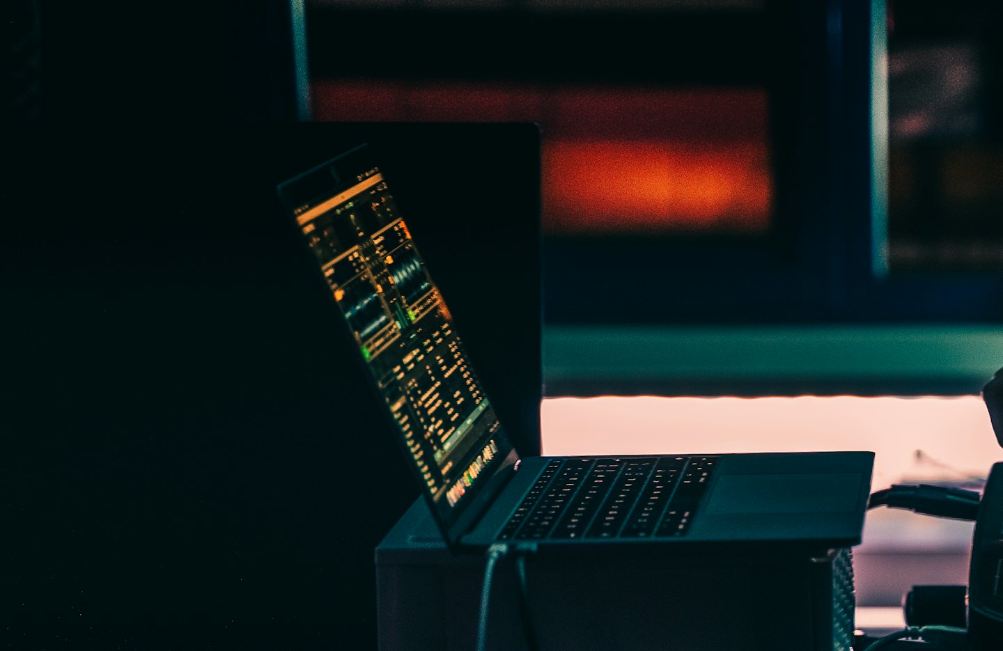 A laptop screen displays complex data visualization and software interfaces.