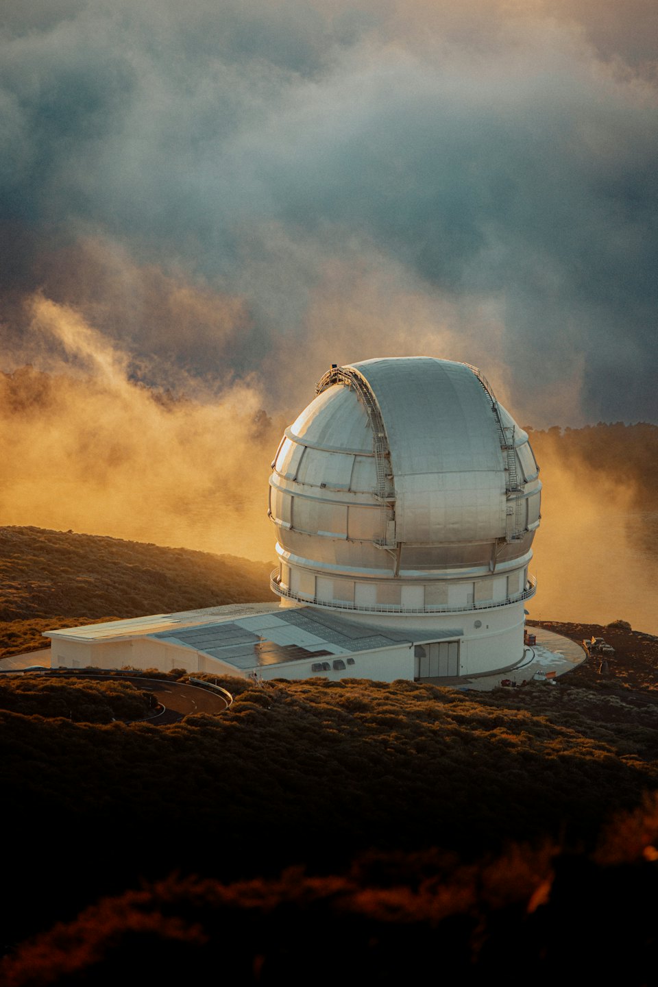 Observatory dome on a hillside at sunrise.